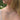 A close-up lifestyle shot of a woman with long blonde hair wearing a ombre rainbow gradient beaded necklace and a white top, with a blurred green outdoor background.