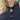 A woman with blonde hair wearing a long black beaded frog necklace with a colorful pendant, 