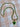 A gold-tone tennis-style necklace with green faceted stones and a green heart-shaped pendant with a dark green center, laid flat on a beige and white checkered fabric background.