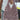A close-up of a person holding a large woven handbag with a loop handle. The bag has an intricate openwork woven pattern in dusty mauve and brown tones with long fringe.