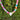 A colorful striped garland with a white heart-shaped pendant, photographed outdoors against a background of green trees.