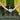 A pink beaded necklace with a smooth, white heart-shaped bead and small gold spacer beads, shown outdoors against a background of green trees and grass.